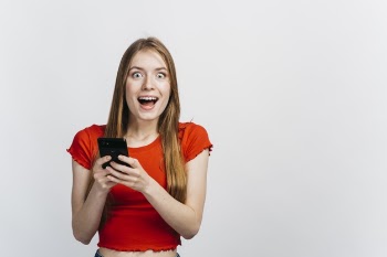 Shocked woman holding her phone with copy space Free Photo