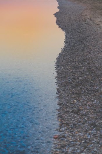 shore beside ocean during sunset