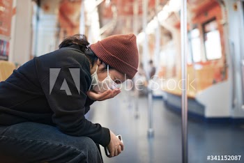 Sick woman in a mask coughing in public during coronavirus pandemic