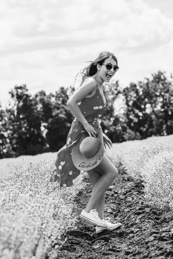 Side View Grayscale Photo of Laughing Woman Floral Dress Standing in Flower Field Posing