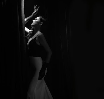Side View Grayscale Photo of Woman in Glamorous Dress Posing With Her Eyes Closed By Curtain