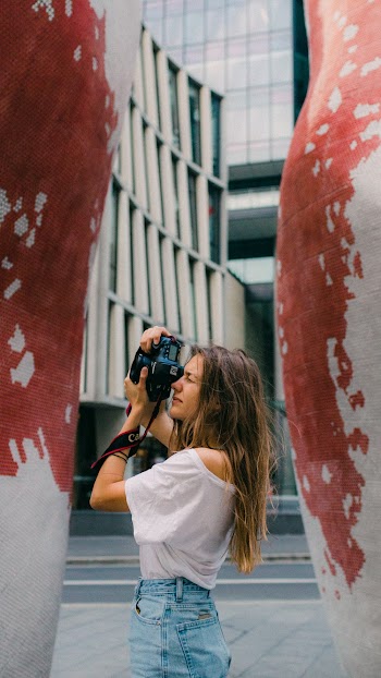 Side View Of A Woman Taking Photo Using A A Digital Camera