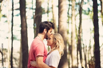 Side view of man kissing woman on forehead in forest