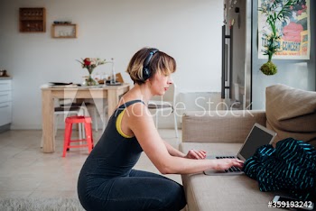 Side view of woman wearing headphones listening to music while using laptop