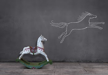 Side view of wooden rocking horse on wooden floor with running horse...