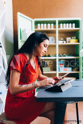 Side view of young woman using smartphone and digital tablet in bar