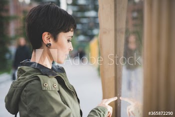 Side view of young woman using touchscreen monitor for payment on street