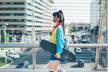 Side view of young woman with skateboard walking on footbridge