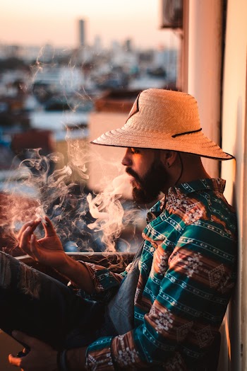 Side view photo of a man in brown and green shirt  smoking cigarette