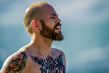 Side View Photo of Bearded Shirtless Man With Chest and Arm Tattoos