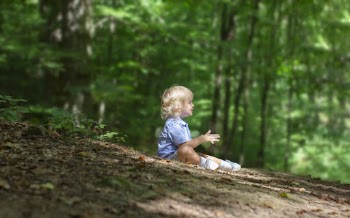 Side View Photo of Boy Sitting on the Ground Alone in the Forest