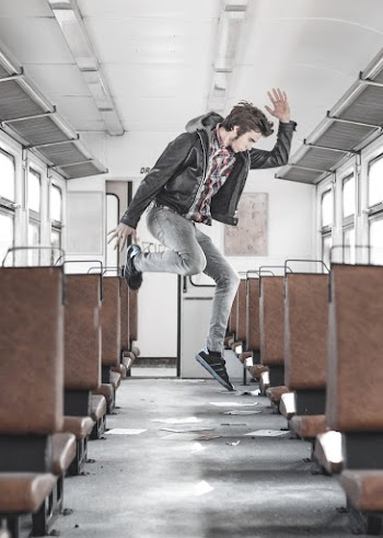 Side View Photo of Man Jumping Inside Train Aisle 