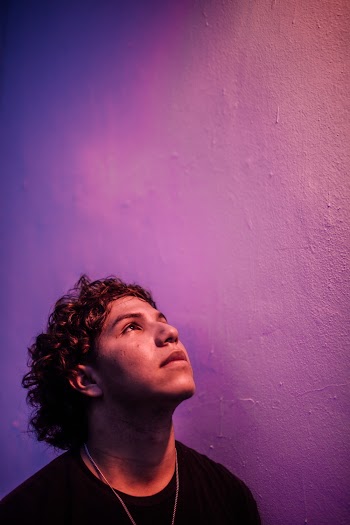 Side View Photo of Man Standing Next To Purple Wall Looking Up