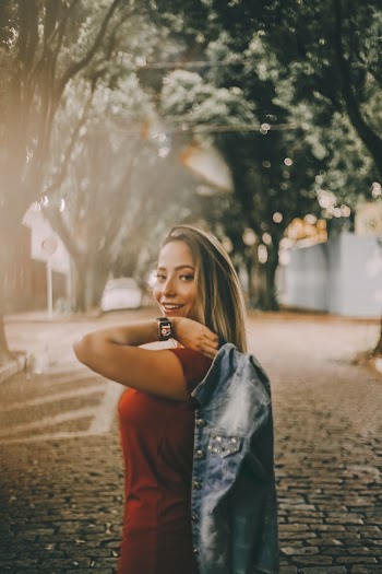 Side View Photo of Smiling Woman Carrying Denim Jacket Over Shoulder Posing