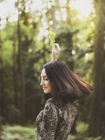 Side View Photo of Smiling Woman Holding Green Leaf