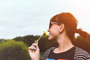 Side View Photo of Smiling Woman Smelling Yellow Flower