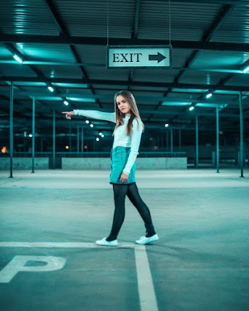 Side View Photo of Standing Woman Posing and Pointing Her Finger in Empty Parking Lot