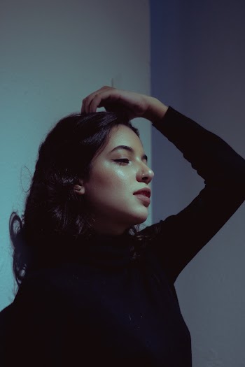 Side View Photo of Woman in Black Long-sleeved Top Posing with Her Hand on Her Hair