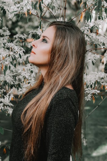 Side View Photo of Woman in Black Top Posing Next to White-petaled Flowers Looking Up
