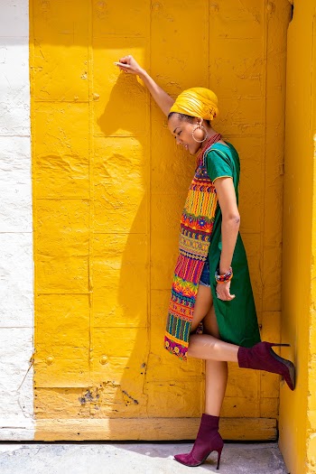 Side View Photo of Woman in Long Dashiki Top Posing by Yellow Wall