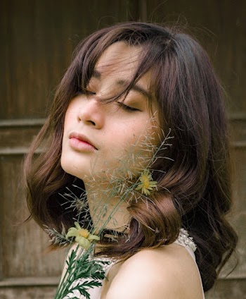 Side View Photo of Woman Posing With Her Eyes Closed Holding Flowers