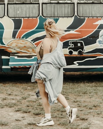Side View Photo of Woman Walking Past Bus