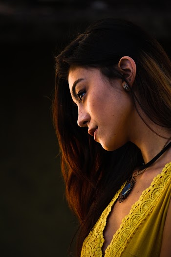 Side view portrait photo of a woman wearing yellow top  