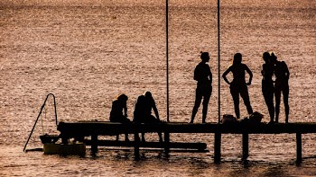 Silhouette of 6 Person on Dock Near the Calm Body of Water