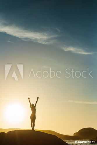 Silhouette of a woman at the beach with her hands raised