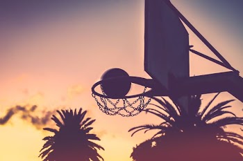 silhouette of basketball hoop and basketball during orange sunet
