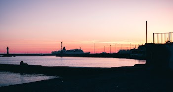 Silhouette of Boat Dock Near Water during Dawn