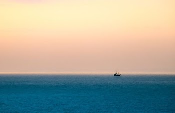 silhouette of boat sailing under cloudy sky during daytime