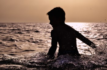 Silhouette of Boy on Body of Water