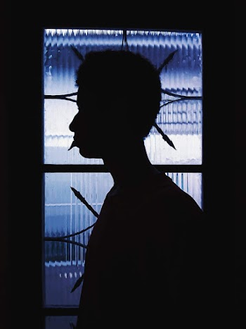 Silhouette of Boy Standing Near Light