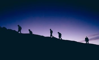 silhouette of five persons walking on hill