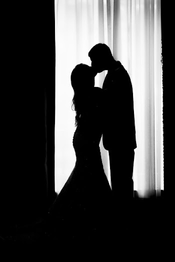 Silhouette of Groom and Bride Kissing Near Window