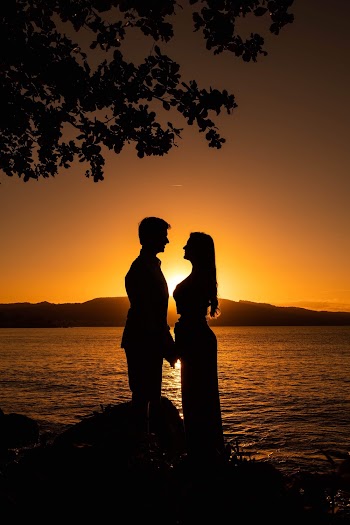 Silhouette of Man and Woman Standing Near Body of Water