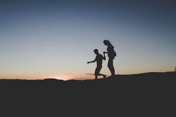 silhouette of man and woman walking on mountain