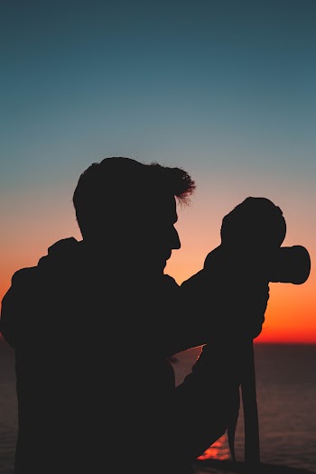 Silhouette Of Man Holding Camera Taking Photo
