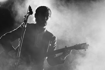silhouette of man playing a guitar beside a microphone