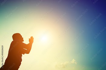 Silhouette of man praying at sunrise.