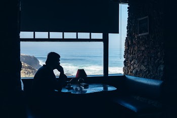 Silhouette of Man Sitting in Front of Table Beside Window