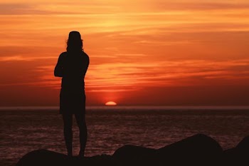 silhouette of man standing near body of water