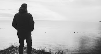 Silhouette of Man Standing Near Body of Water