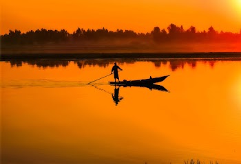 Silhouette of Man Standing on Boat in the Middle of the Lake