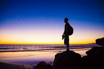 silhouette of man standing on cliff