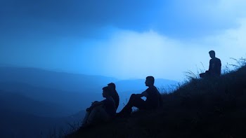 silhouette of men sitting on mountain