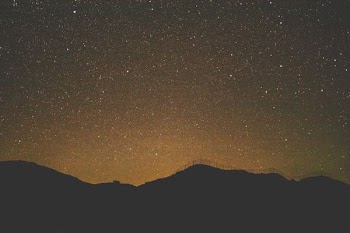 silhouette of mountain under starry night sky