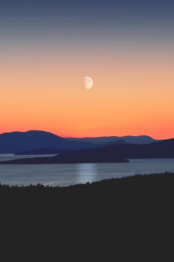 silhouette of mountains next to body of water