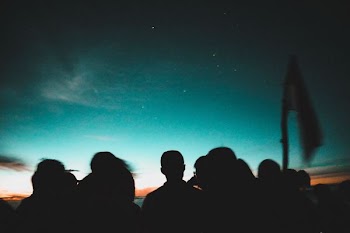 silhouette of people facing on the sky
